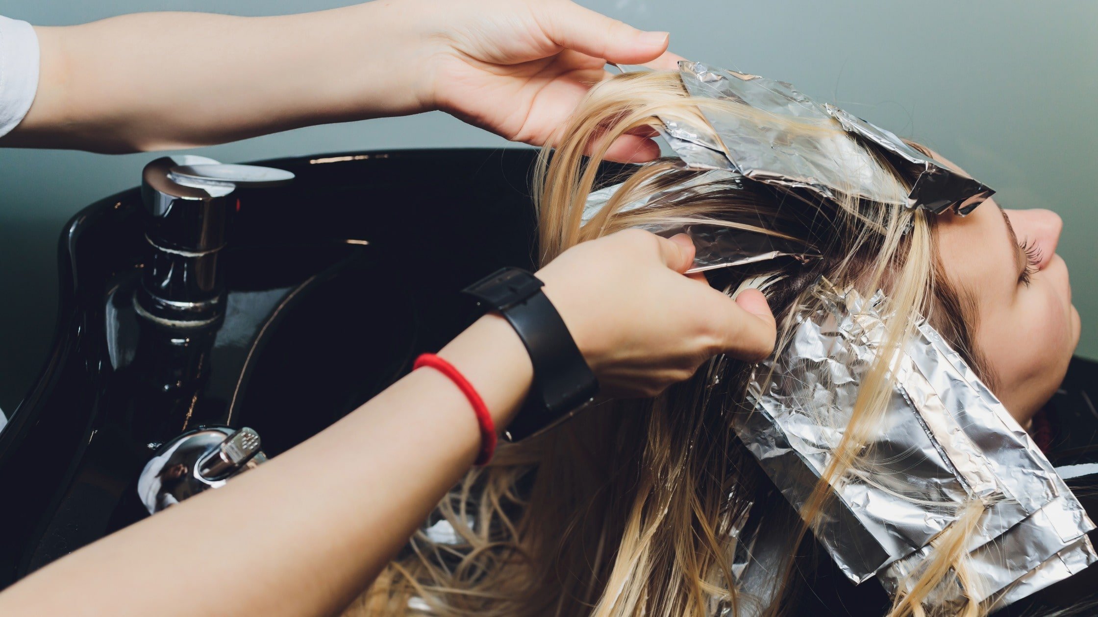 Donna con capelli biondi e babylight naturale durante trattamento in salone parrucchiere a Milano